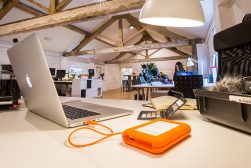 a laptop computer sitting on top of a white table next to orange external drive