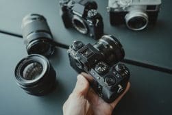 A hand holding several cameras on a table.