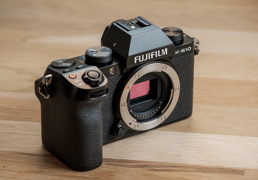 The fujifilm x-e1 is sitting on a wooden table.