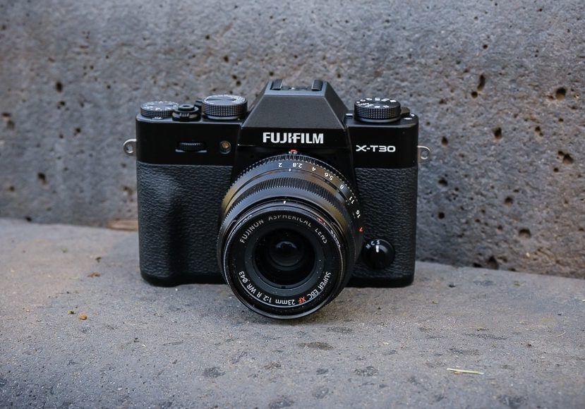 The fujifilm x100t is sitting on a concrete wall.