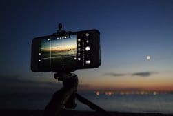 A cell phone on a tripod with the moon in the background.
