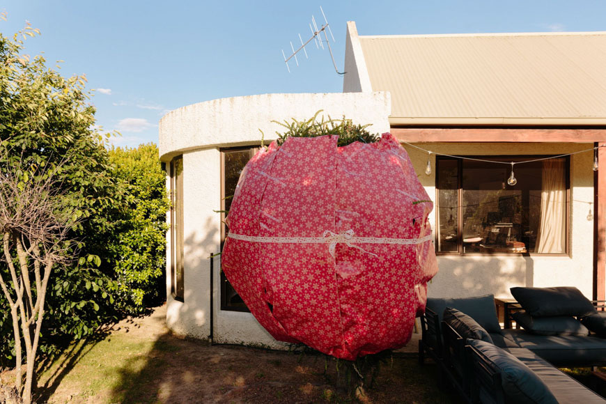 A large pink present sitting outside of a house.