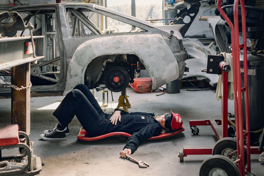 A mechanic laying on the floor of a garage.