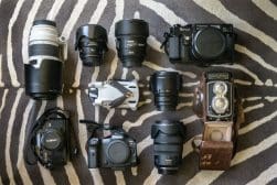 A group of cameras and lenses laid out on a zebra print.
