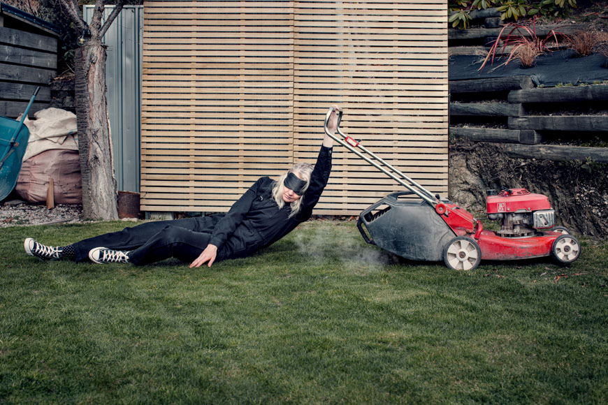 A man laying on the ground with a lawn mower.