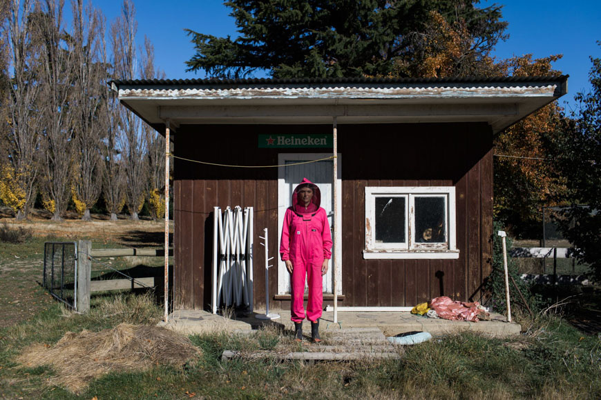 A woman in a pink jumpsuit standing in front of a small house.