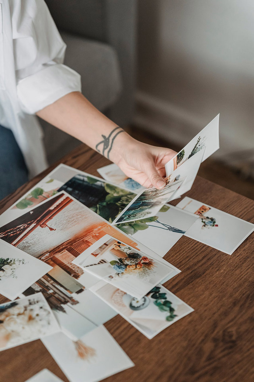 A woman holding a stack of photos on a table.