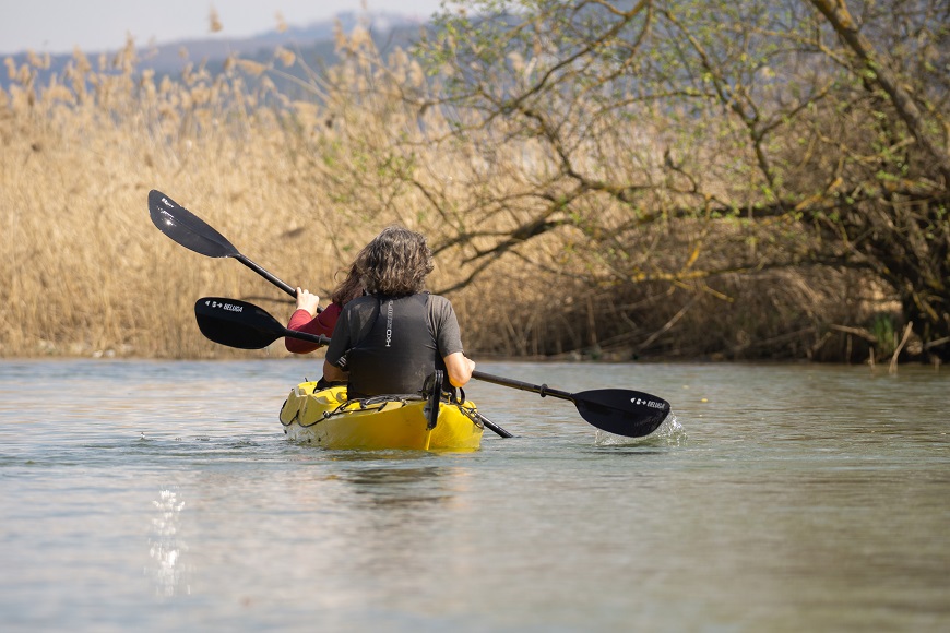 A woman is paddling a kayak on a river.