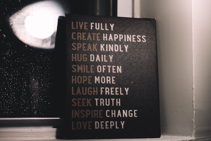 A wooden sign that says live fully happiness create kindness smile often.