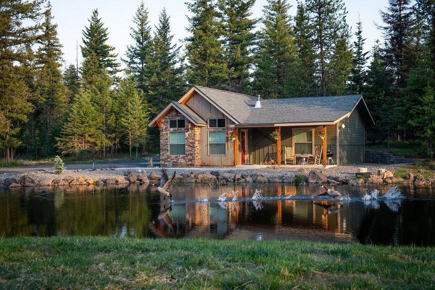 A cabin in the woods next to a pond.