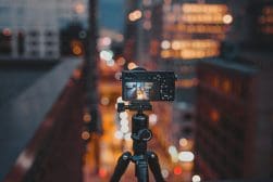 A tripod with a camera in front of a city at night.